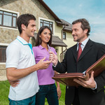 Young couple signing renting contract with real estate agent. agent giving pen to sign agreement for house sale