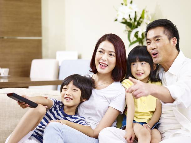 A young Singaporean family watching television together