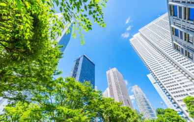 Asia Business concept for real estate, corporate construction and ecology - looking up view of panoramic modern city skyline with blue sky and green tree in shinjuku, tokyo, japan