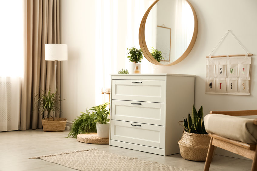 Stylish room interior with chest of drawers and round mirror