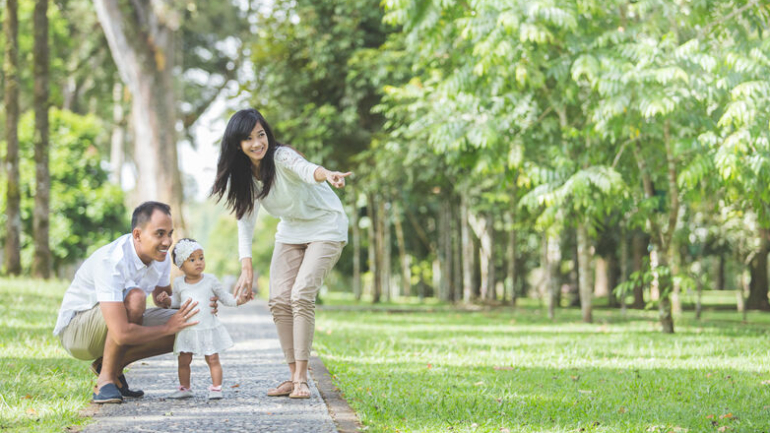 portrait of Beautiful family with cute baby in the park having fun together